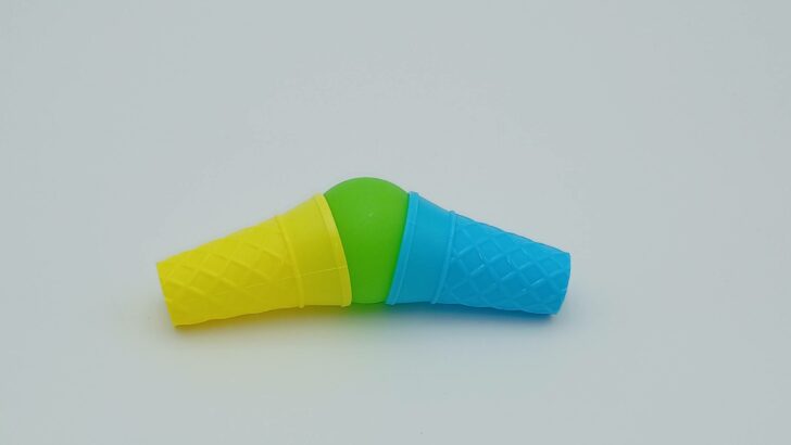 A player is attempting to scoop up a dropped green scoop of ice cream using their yellow and blue cones.
