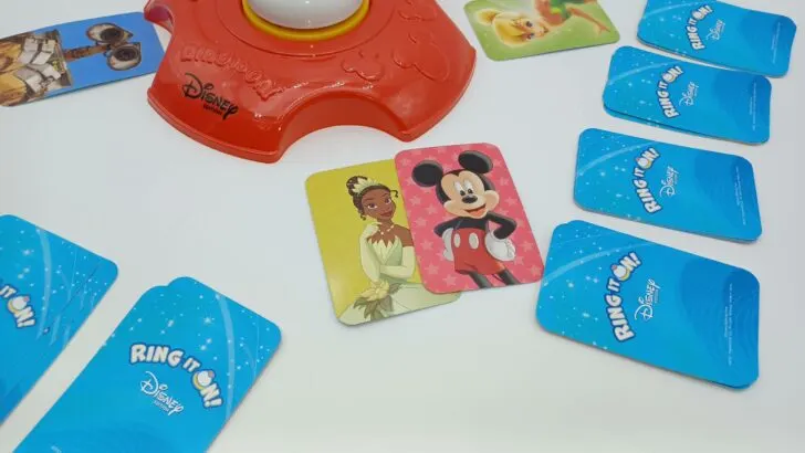 This picture shows the player taking the Tiana card by the game tray and giving up their Mickey Mouse card in exchange.