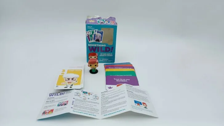 This picture shows all of the components of Something Wild!: The Little Mermaid including the box, small Ariel figure, the Character cards, the Power cards, and the instructions.