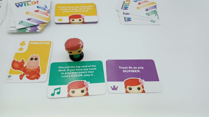 This picture shows a player with the Ariel figure and three possible Power cards they could use: two of their own and the Power card in the middle of play.