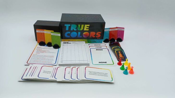 A picture of all of the components included in the True Colors box including a voting box, six colorful player cards with stands, the instructions, a score pad, three oversized cards (containing the words "most," "some," and "none), voting cards, question cards, and tokens.