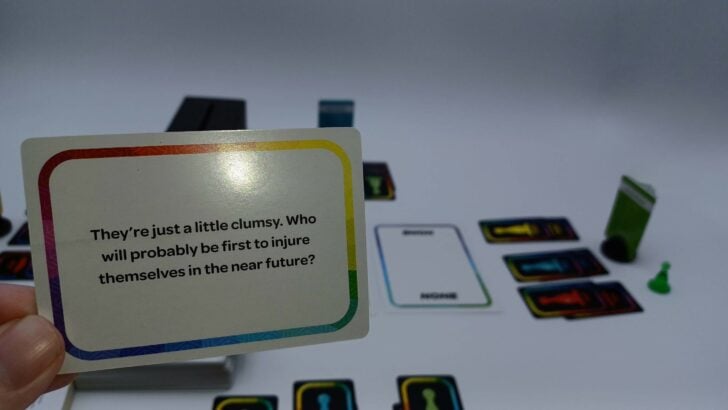 A picture of a player reading a card in True Colors. The card's text says "They're just a little clumsy. Who will probably be first to injure themselves in the near future?"