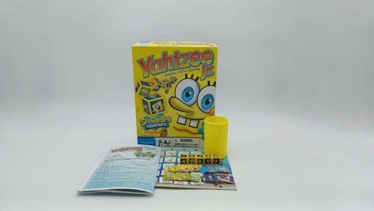 This picture shows all of the components included in Yahtzee Jr.: SpongeBob SquarePants including a box, instructions, a yellow dice cup, five dice, and four sets of tokens (yellow, green, blue, and purple).