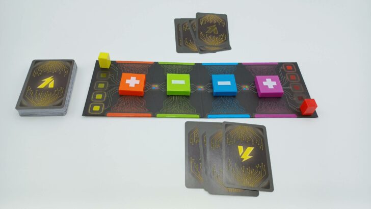 A picture of the setup for Voltage. The board is placed in the middle with the orange and purple terminal tokens set to + and the green and blue set to -. Both players have also been dealt four cards.